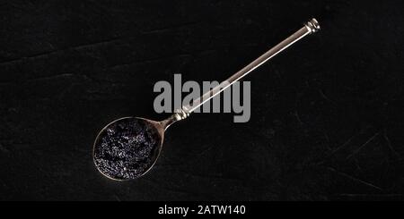 Caviar noir sur un panorama de la cuillère d'argent, tiré du dessus sur un fond sombre avec un endroit pour le texte Banque D'Images