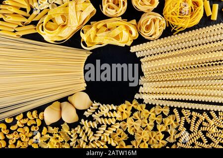 Les pâtes italiennes avec copie espace, d''une télévision jeter d'une variété de types de pâtes, tourné à partir de ci-dessus, sur un fond noir avec une place pour le texte Banque D'Images