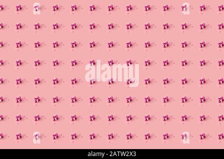 petites boîtes cadeaux à motifs créatifs décorées de noeuds roses en satin et de coeurs roses sur un fond rose pastel Banque D'Images