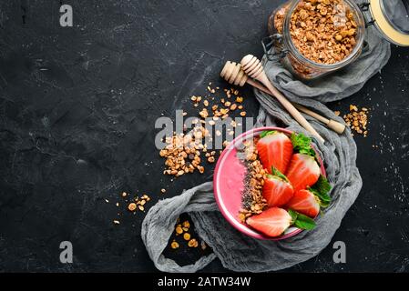 Bol à smoothie avec fraises fraîches, céréales, yaourt et graines de chia. Petit Déjeuner. Vue de dessus. Espace libre pour votre texte. Banque D'Images