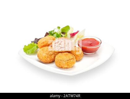 Pépites de poulet croustillant frit chaud dans la pâte et le sésame sur une plaque blanche avec ketchup et laitue. Viande Croquante Panée De Poulet. Isolé Banque D'Images