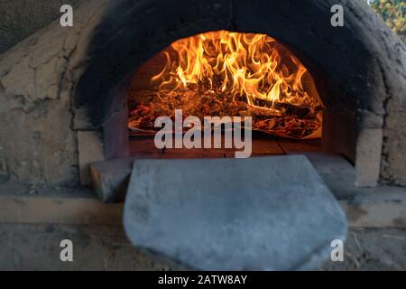 Pizzas cuisinant dans la pierre et rafles four à pizza. Scène de cuisine traditionnelle, arrière-plan Banque D'Images