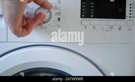 Homme Utilisant Un Lave-Linge Moderne Appareil Pour Laver Et Nettoyer Les Vêtements Sales Banque D'Images