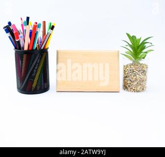 Un modèle de plaque en bois vide le long d'un arbre miniature et d'un porte-crayon plein de crayons de couleur différente Banque D'Images