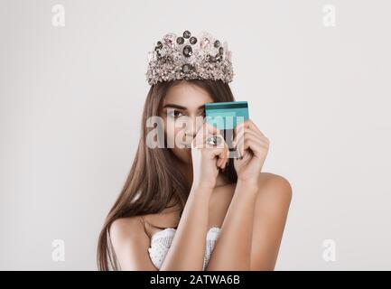 Pour être beau j'ai besoin de ma carte de crédit. Mode modèle femme jolie fille tenant montrant carte bancaire en plastique souriant heureux. Grand matc. Couronne de beauté sombre Banque D'Images