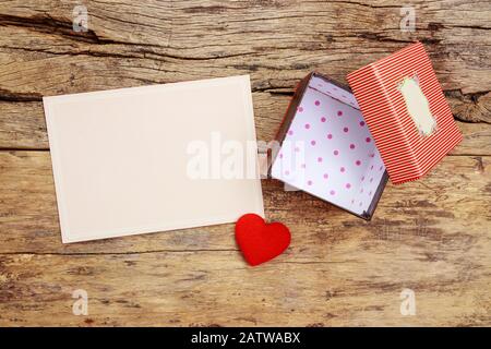 carte de vœux rose vierge avec cadre de bordure et coffret cadeau rouge vide avec couvercle ouvert, décorer avec coeur rouge sur fond en bois Banque D'Images