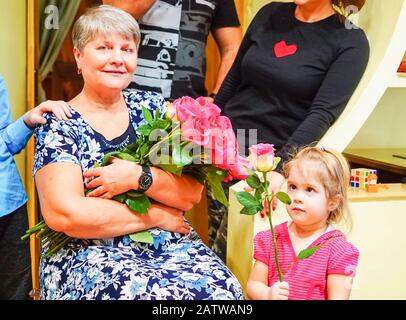 La fille félicite sa grand-mère et donne des fleurs Banque D'Images