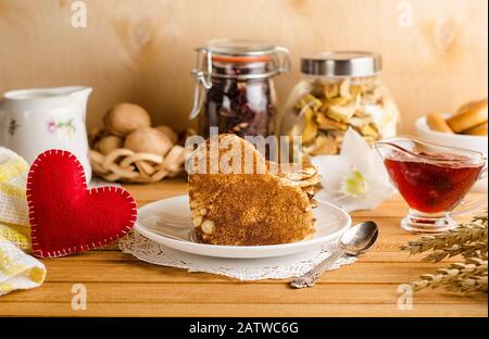 Beignets, crêpes sous forme de coeurs avec confiture sur un fond en bois clair avec un coeur rouge, petit déjeuner romantique pour la Saint-Valentin. Fête Des Mères. Banque D'Images