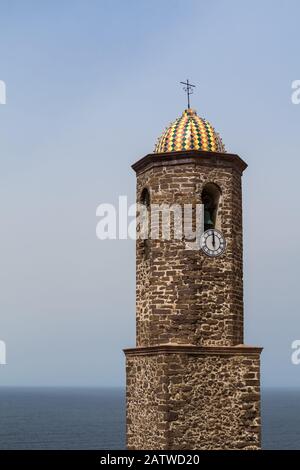 Dôme coloré dans une tour d'une église Saint Anthony à Castelsardo, en Sardaigne, en Italie. Horizon de la mer méditerranée et ciel bleu en arrière-plan. Banque D'Images