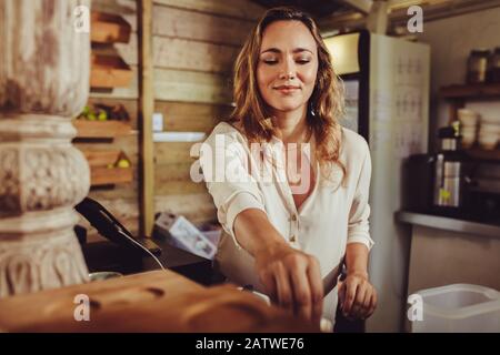 Femme travaillant dans un café. Jeune barista féminin se tenant derrière le bar dans un café et travaillant. Banque D'Images