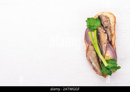 Sandwich avec des spats, des oignons et du persil, sur fond de bois. Vue de dessus. Espace de copie. Banque D'Images