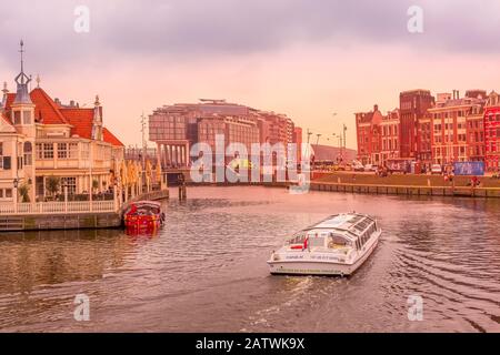Amsterdam, Pays-Bas - 2 avril 2016 : vue sur la rue au coucher du soleil avec maisons anciennes traditionnelles, canal et bateau Banque D'Images