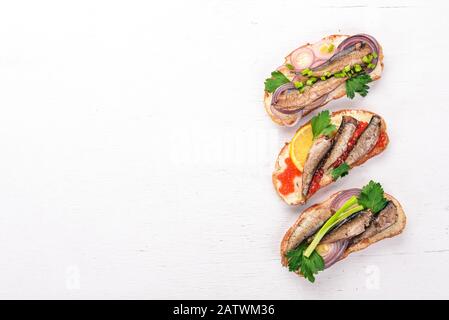 Un ensemble de sandwichs avec des sprats, du caviar, de l'oignon et du persil, sur fond de bois. Vue de dessus. Espace de copie. Banque D'Images