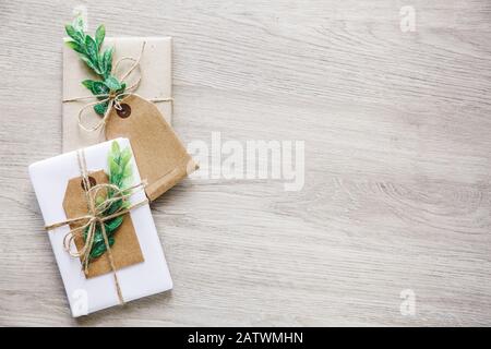 Composition avec boîtes cadeaux de style naturel artisanales, éléments de décoration florale et noeud de ficelle rustique sur fond en bois. Banque D'Images