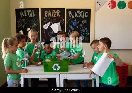 Groupe d'écoliers portant des t-shirts verts avec un logo de recyclage blanc sur eux debout autour d'un Banque D'Images