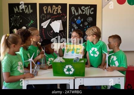 Groupe d'écoliers portant des t-shirts verts avec un logo de recyclage blanc sur eux debout autour d'un Banque D'Images