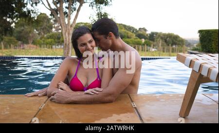 Un jeune couple heureux se tenant dans la piscine Banque D'Images