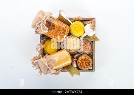 Un ensemble de moutarde dans une boîte en bois. Épices Sur fond blanc en bois. Vue de dessus. Espace de copie pour votre texte. Banque D'Images