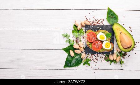 Sandwich aux œufs de caille, aux avocats, aux tomates cerises et aux pistaches. Sur un fond en bois. Vue de dessus. Espace libre pour votre texte. Banque D'Images