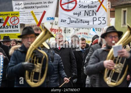 Berching, Allemagne. 05 février 2020. Joachim Herrmann (CSU, centre l), ministre bavarois de l'intérieur, se rend sur le marché du cheval Berching entre musiciens et devant des adversaires de la ligne de pouvoir qui tiennent des affiches de protestation. Le Berchinger Rossmarkt est considéré comme le plus grand festival folklorique d'hiver de l'État libre. Crédit: Armin Weigel/Dpa/Alay Live News Banque D'Images