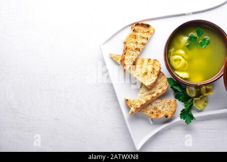 Bouillon de ravioli et herbes. Cuisine italienne. Sur un fond en bois. Vue de dessus. Espace libre pour votre texte. Banque D'Images