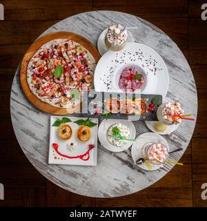 Restaurant. Une table avec des desserts délicieux et intéressants pour les enfants. Crème glacée, Cocktails et Plaquettes Thermoformées sur les assiettes. Cuisine gaie. Banque D'Images