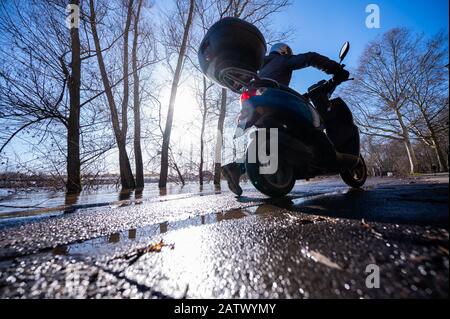 05 février 2020, Hessen, Wiesbaden: Un homme pousse son scooter à travers des flaques d'eau sur les rives du Rhin dans le district de Wiesbaden de Mayence-Kostheim. Les rives du Rhin dans le district de la capitale de l'État sont partiellement inondées, mais encore praticables pour les piétons et les cyclistes. Photo: Andreas Arnold/Dpa Banque D'Images