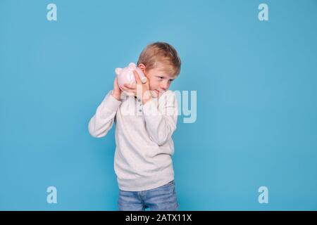 Mignonne petit garçon secouant la boîte piquante sur fond bleu Banque D'Images