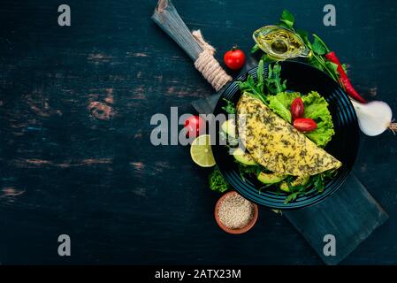 Omelette avec légumes et avocats. Œufs frits. Sur un fond en bois. Vue de dessus. Espace de copie disponible. Banque D'Images