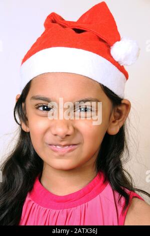 Mumbai, Maharashtra, Inde- Asie, 29 décembre 2014 - Heureuse petite fille indienne portant Red Santa Claus Hat célébrant le festival de Noël. Banque D'Images