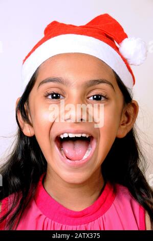 Mumbai, Maharashtra, Inde- Asie, 29 décembre 2014 - Heureuse petite fille indienne portant Red Santa Claus Hat célébrant le festival de Noël. Banque D'Images