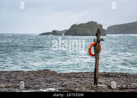 Un preserrateur de vie accroché sur un poteau près de l'océan sur la côte d'Antrim en Irlande du Nord pour être facile à utiliser pour sauver des personnes dans une émergence dans la mer Banque D'Images