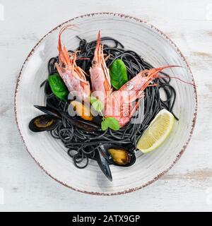 Spaghetti noir. Pâtes noires avec fruits de mer et citron. Crevettes et moules. Sur l'arrière-plan ancien. Vue de dessus. Espace libre pour votre texte. Banque D'Images