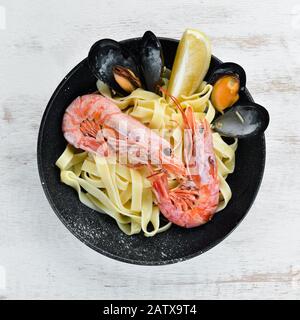 Pâtes avec fruits de mer et citron dans une assiette. Crevettes, moules. Sur l'arrière-plan ancien. Vue de dessus. Espace libre pour votre texte. Banque D'Images