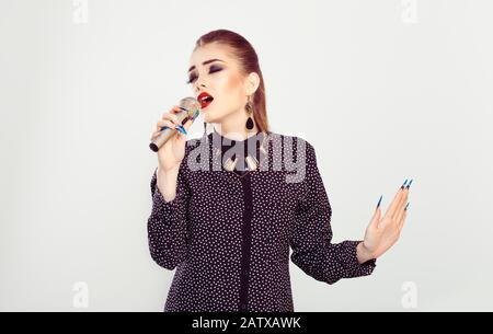 Chanteur. Femme jouant chanter au microphone avec toutes ses passion coeur force yeux fermé isolé mur blanc arrière-plan. La beauté avec les lèvres rouges fume b Banque D'Images