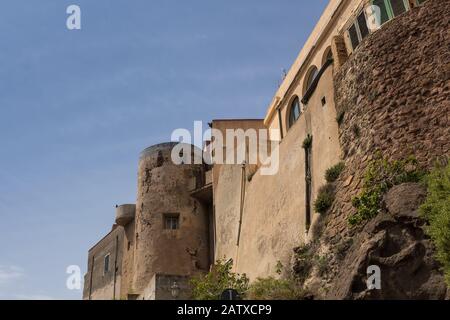 Colline avec la diagonale des bâtiments du château. Tour en pierre. Ciel bleu avec nuages légers au printemps. Castelsardo, Sardaigne, Italie. Banque D'Images