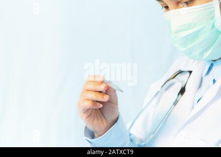 Le coronavirus arrête l'infection. Le jeune médecin porte un masque avec thermomètre et stéthoscope contre les maladies infectieuses et la grippe. Santé, médical Banque D'Images