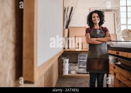 Jeune femme souriant tout en se tenant dans son studio de cadrage d'image Banque D'Images