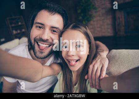 Photo de belle petite drôle dame sa jolie jeune papa s'asseoir confortable sofa faisant prendre des selfies en dehors de la bouche passer le week-end maison de temps Banque D'Images