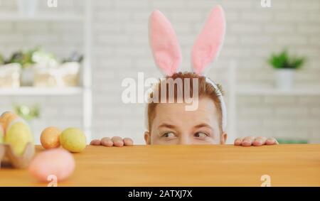 Joyeuses pâques.un drôle de gros homme décorent les œufs en s'asseoir à une table avec le décor de Pâques en arrière-plan Banque D'Images
