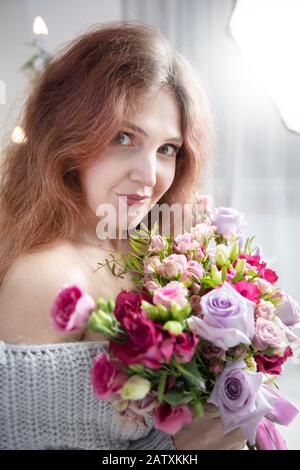 Portrait vertical d'une belle femme à poil long avec un bouquet de fleurs Banque D'Images