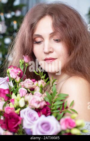 Portrait vertical d'une belle femme à poil long avec un bouquet de fleurs Banque D'Images