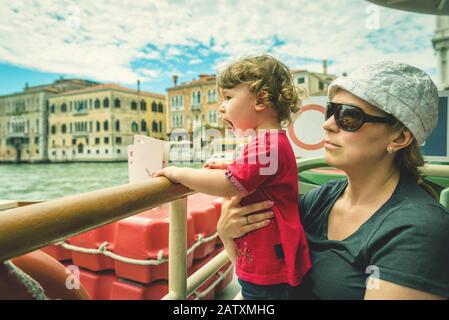 L'enfant mignon hurle avec plaisir, étant avec sa mère sur un bateau touristique sur le Grand Canal à Venise. Le Grand Canal est l'un des principaux cours d'eau Banque D'Images