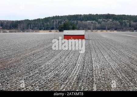 Grange en bois rouge dans un champ légèrement couvert de neige en hiver. Sauvo, Finlande. 26 Décembre 2019. Banque D'Images