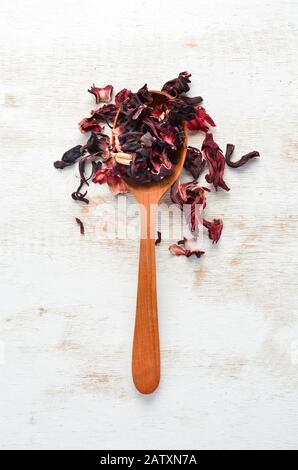 Thé hibiscus rouge dans une cuillère en bois. Sur un fond rustique. Vue de dessus. Espace libre pour votre texte. Banque D'Images