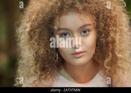 Portrait de la jeune belle femme avec des cheveux blond frisé regardant l'appareil photo Banque D'Images