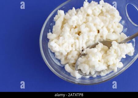 Grains de kéfir dans un bol en verre sur fond bleu gros plan Banque D'Images