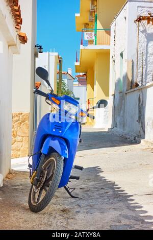 Perdika, île d'Aegina, Grèce - 14 septembre 2019: Petite rue avec scooter à moteur stationné à Perdika Banque D'Images