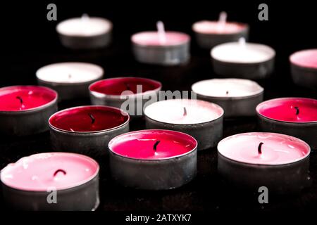 Un ensemble de bougies de paraffine chauffe-plat rose sur fond noir. Banque D'Images