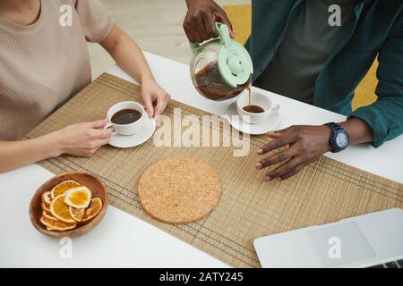 Gros plan sur les jeunes assis à la table et en dégustant une tasse de café dans la cuisine Banque D'Images